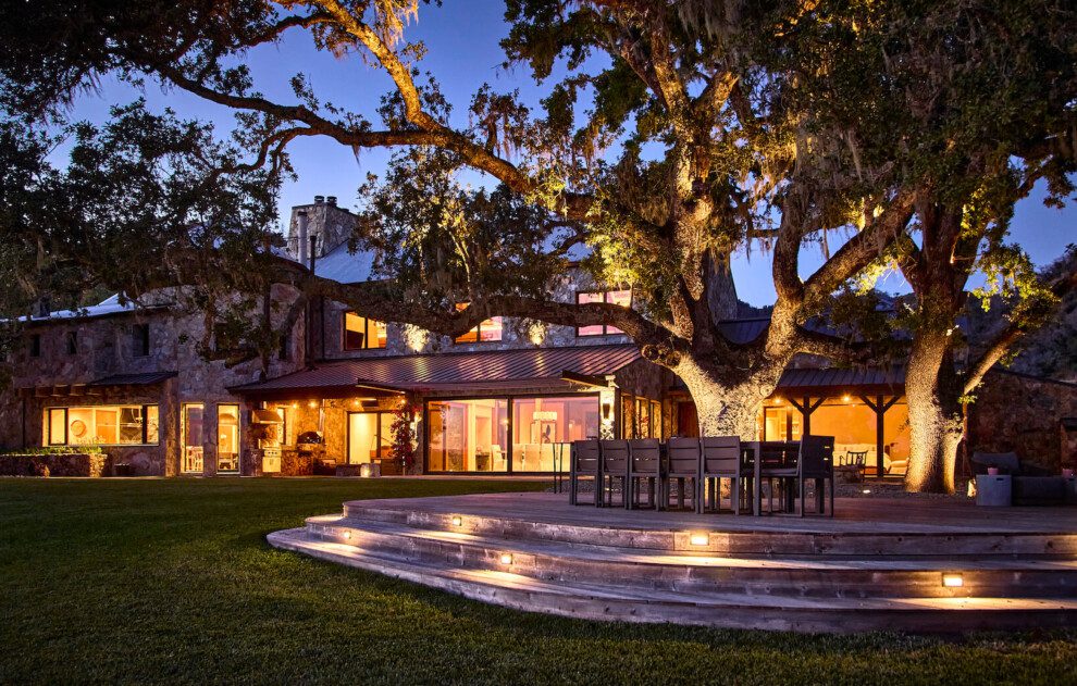 The Residence is lit up at night behind a large oak tree